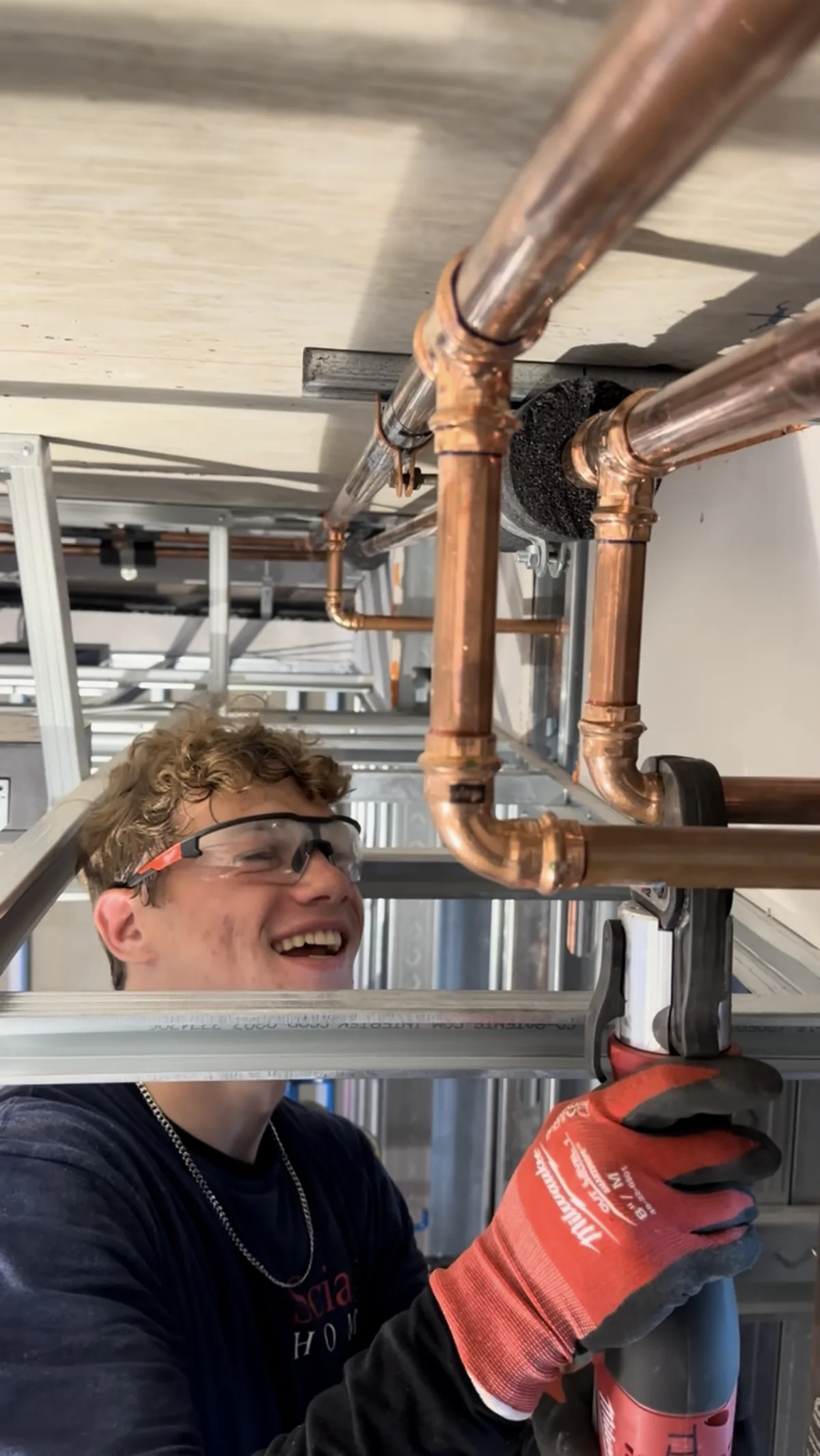 Tier One technician carefully working on copper piping with protective glasses and gloves