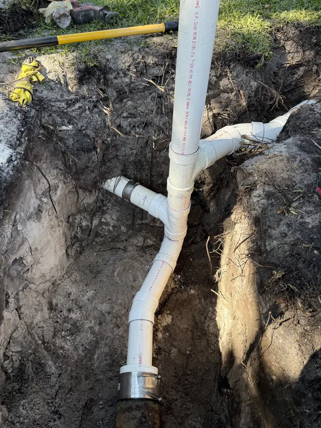 New PVC drain tie-in connected to existing sewer line in an excavated trench