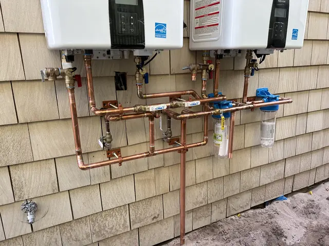 Two tankless water heaters with a copper manifold and filtration installed by Tier One Plumbing