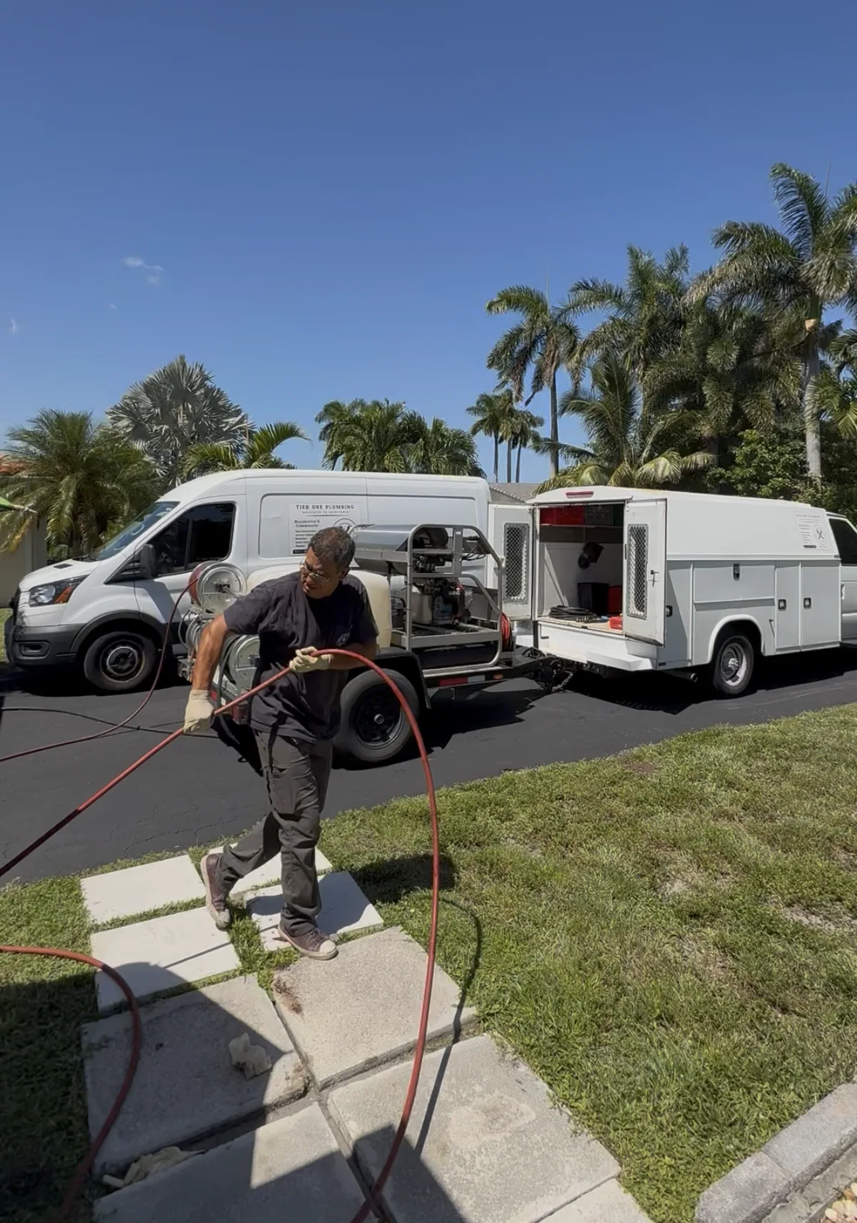 Tier One technician at a residential service visit with the company's plumbing service vehicles