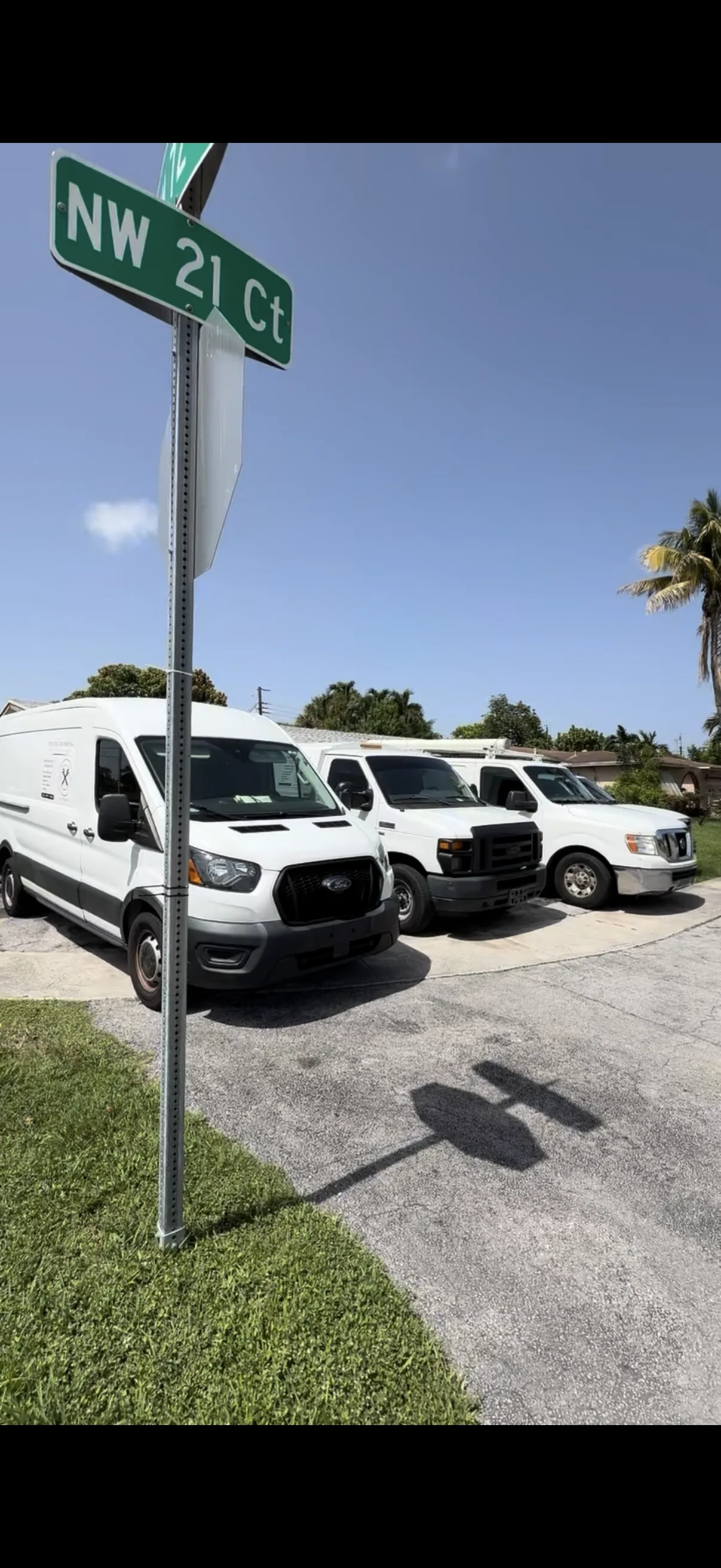 Three white Tier One Plumbing service vehicles parked on NW 21 Ct in a South Florida neighborhood